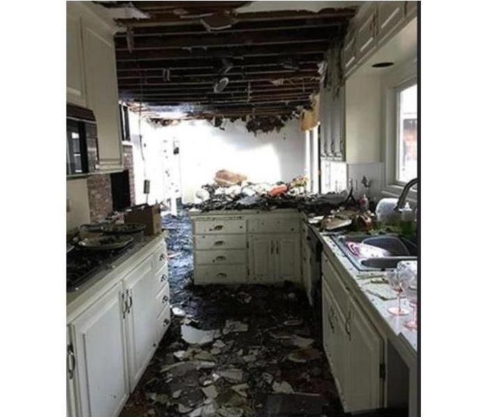 Kitchen fire with a large amount of damage done to ceiling, cabinets, & dining area across from kitchen