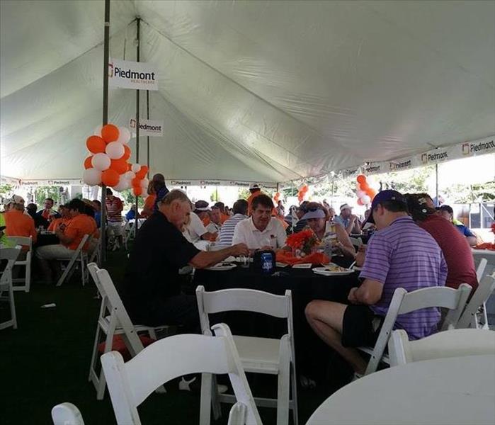 A gathering of people under an event tent seated at tables