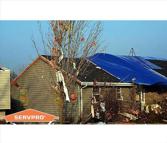 A roof that has been damaged by a storm & covered with a tarp 