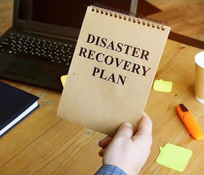 Man holding notebook that says Discovery Recovery Plan??